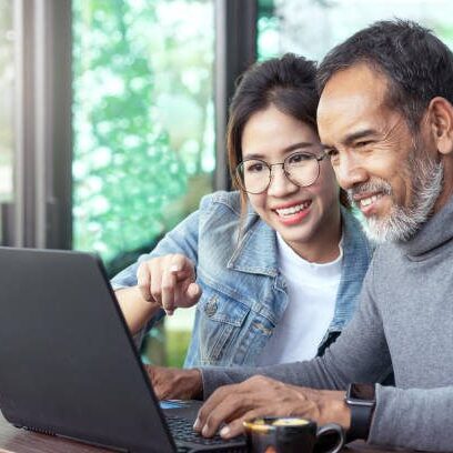 Smiling older man and woman using laptop